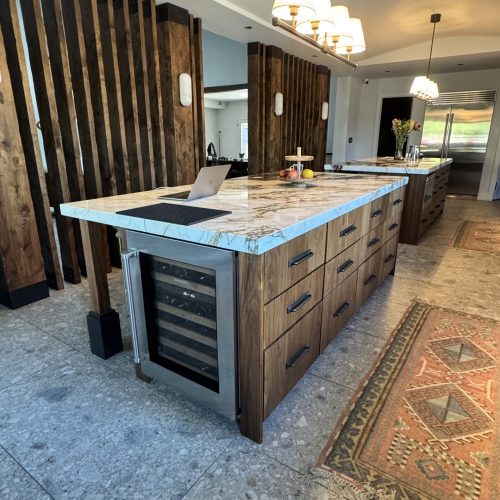 Kitchen with custom walnut cabinets, two islands, marble countertops, and a full-height marble backsplash.