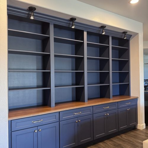 Custom birch bookshelves and lower cabinets painted dark blue with a walnut countertop.