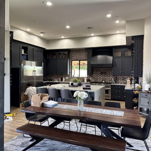 Kitchen with custom navy blue cabinets, a large gray quartz island, and a brick-pattern backsplash.